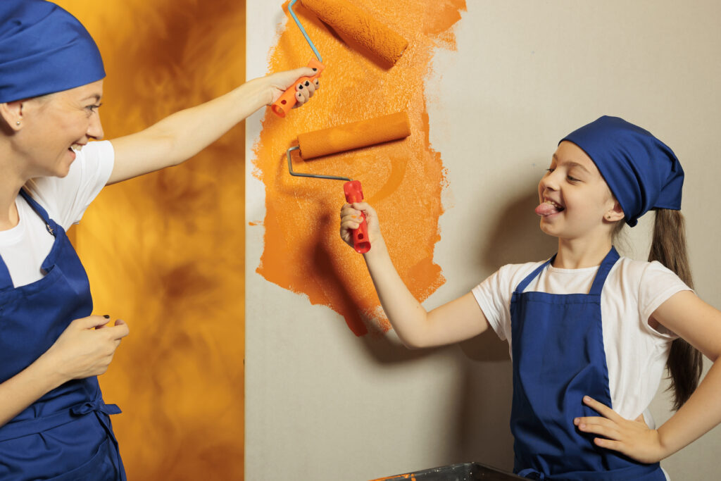 mère et fille qui peignent un mur en orange qui s'amusent